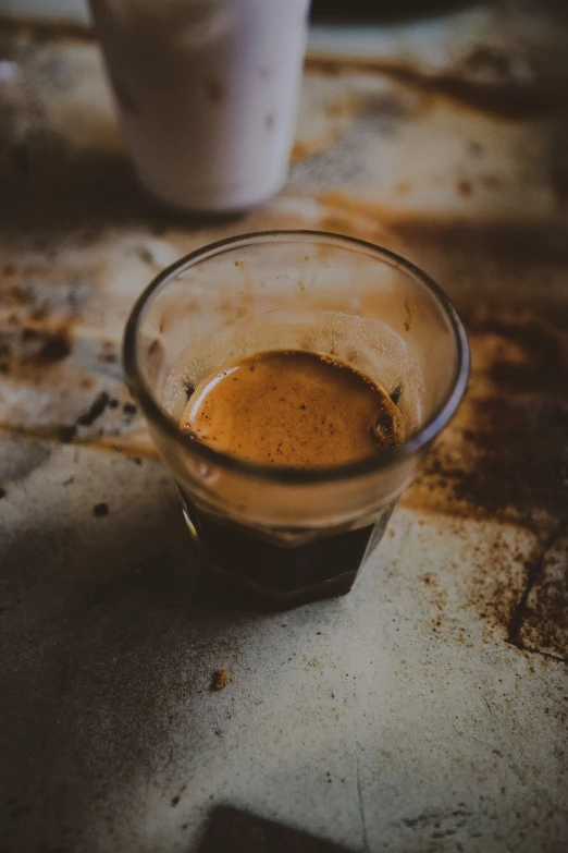 a glass full of brown liquid sitting on a counter