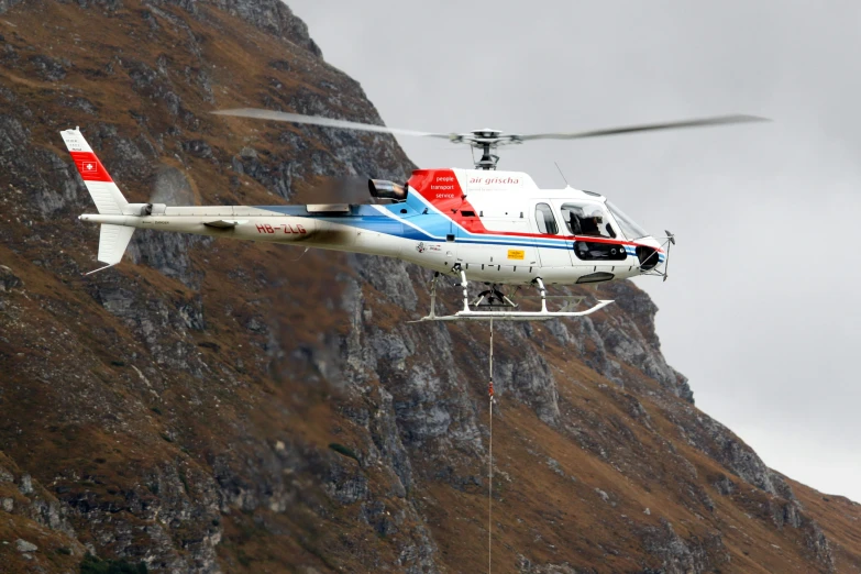 a red, white and blue helicopter with one landing gear raised