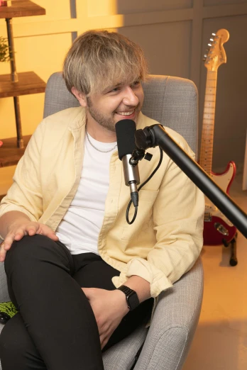 the man is smiling while sitting in front of the microphone