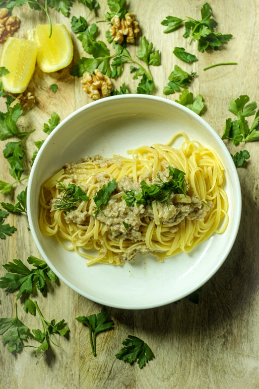 a white plate topped with pasta and meat on top of a table