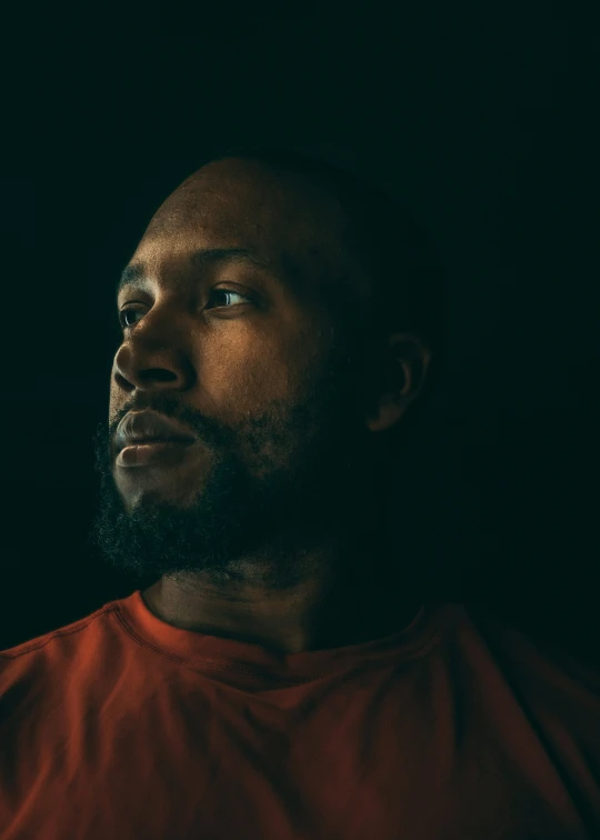 a man with a beard stares upward into the night