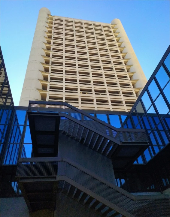 a large tall building with glass windows and staircases next to it