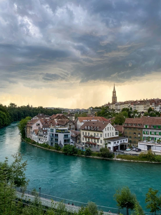 a city next to the river under a cloudy sky