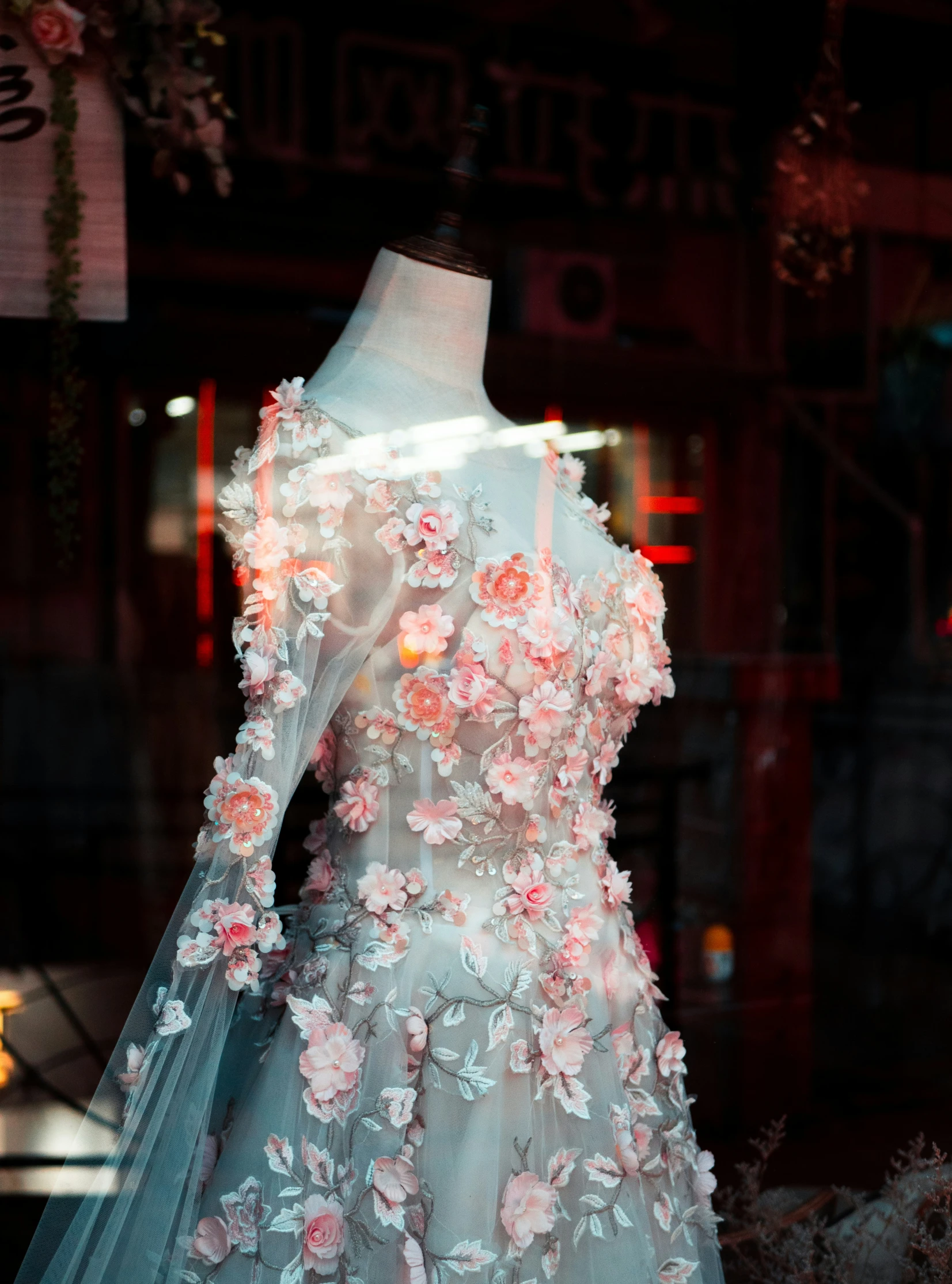 an open - air wedding gown is displayed in a shop window