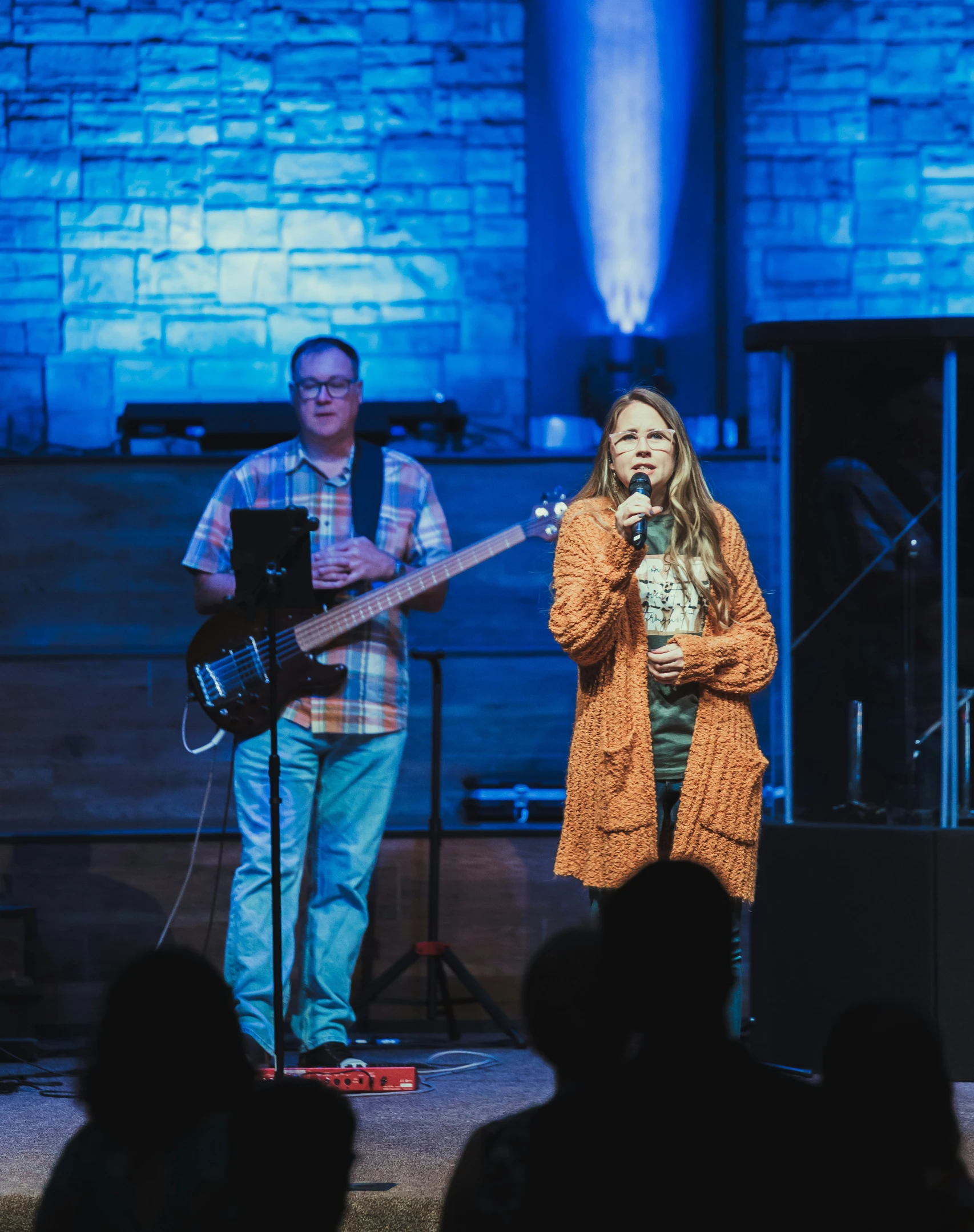 woman singing at a concert with guitar on stage