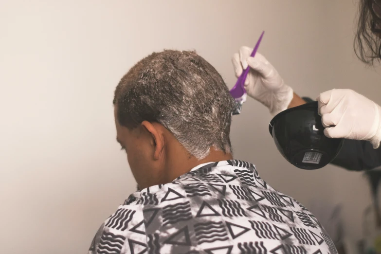 a man with a white glove is having his hair cut