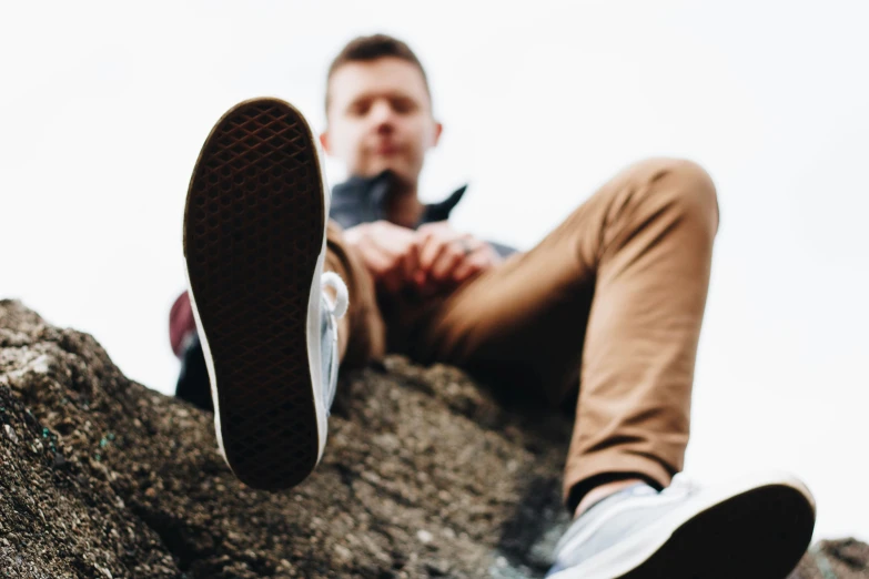 a man sitting on a rock wearing brown pants