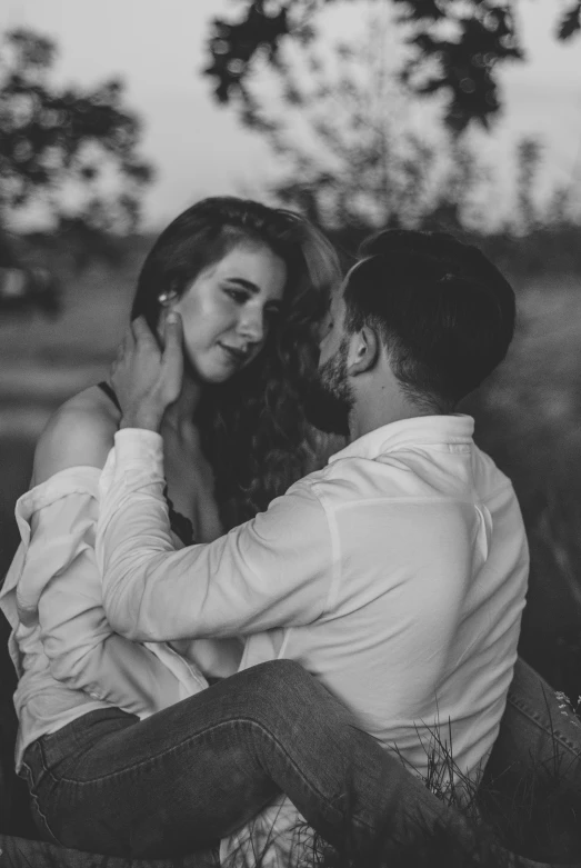 the young couple is sitting together in the field