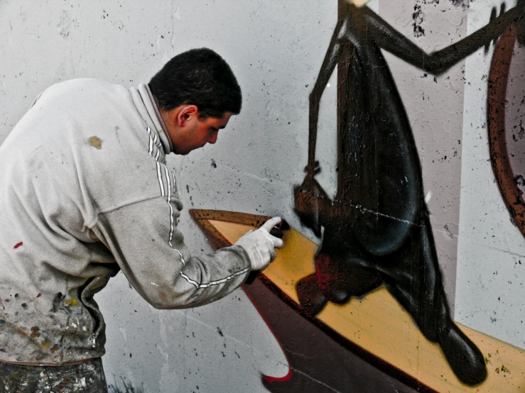 the man is painting the sculpture and putting on gloves