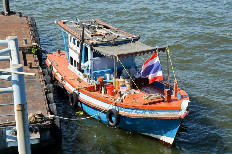 an orange boat parked next to a dock with two men on it