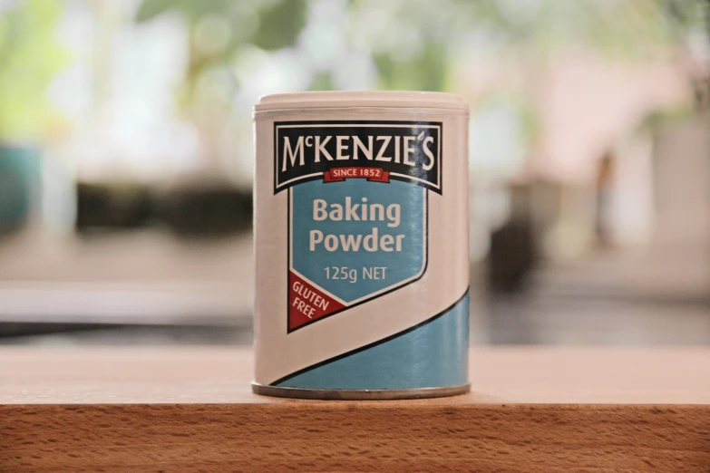 the can of baking powder sits atop a wooden surface