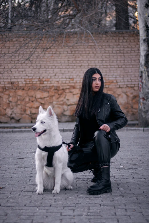 a woman is sitting next to a white dog on a leash