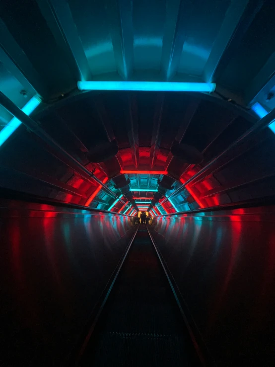 an empty tunnel is lit with red and blue lights