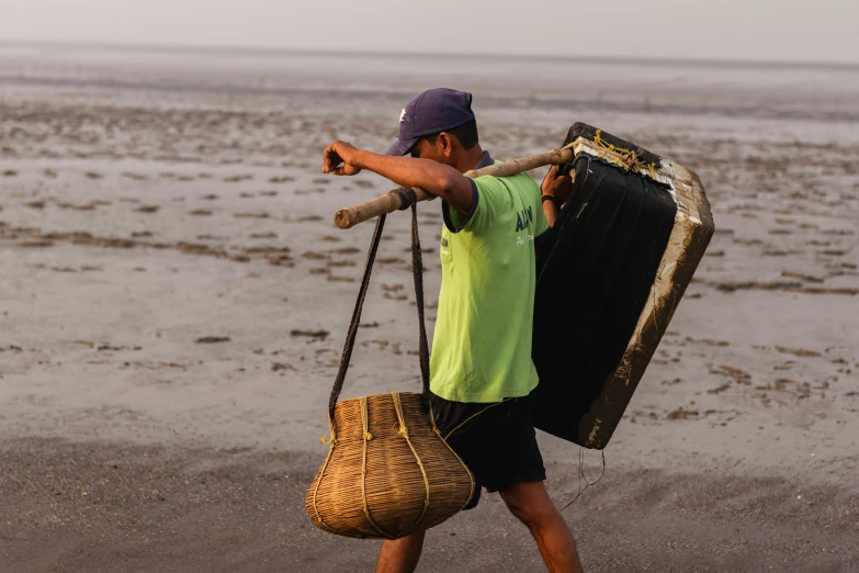 a  walking along the beach carrying luggage