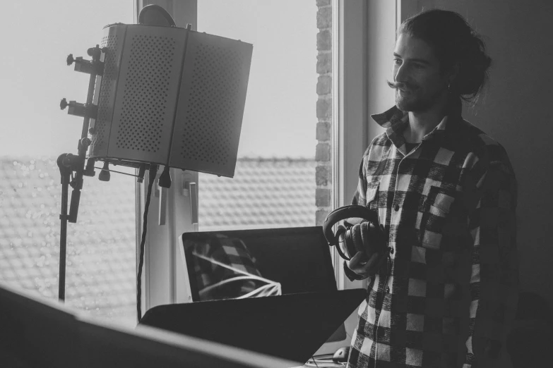 black and white po of young man in recording studio looking out window with music board