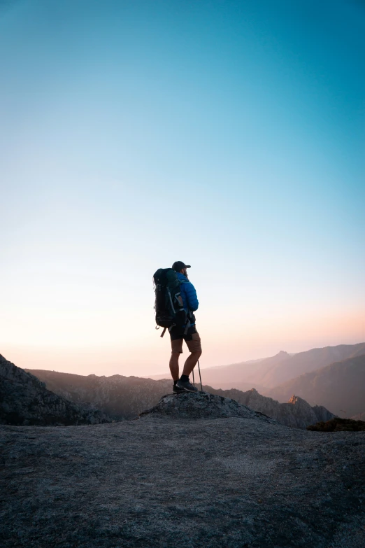 two people stand on top of a mountain at sunset