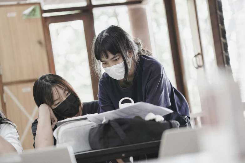 three girls work on laptops at desk wearing face masks