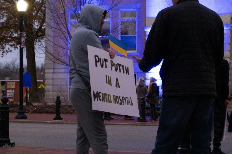 two people stand together holding protest signs