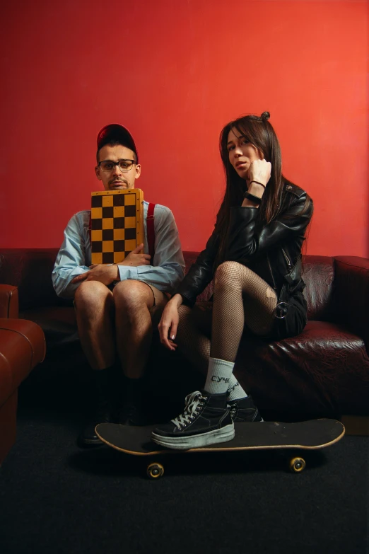 a man and woman sitting on a couch with skateboards