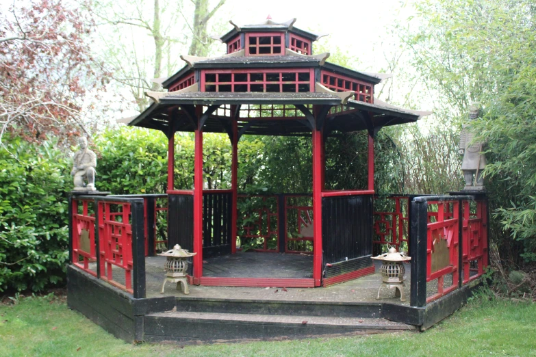 a red and black pavilion in a green park