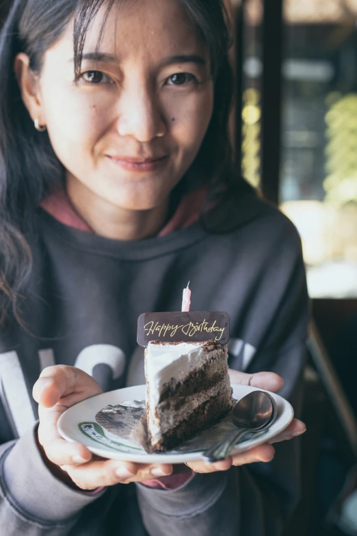 an asian lady holding a piece of cake