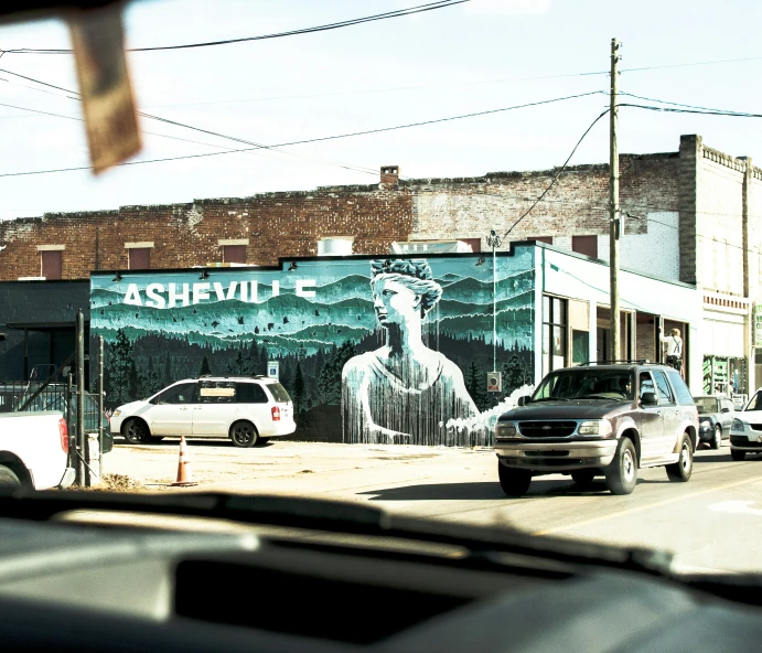 street scene with parked cars and a mural on the wall