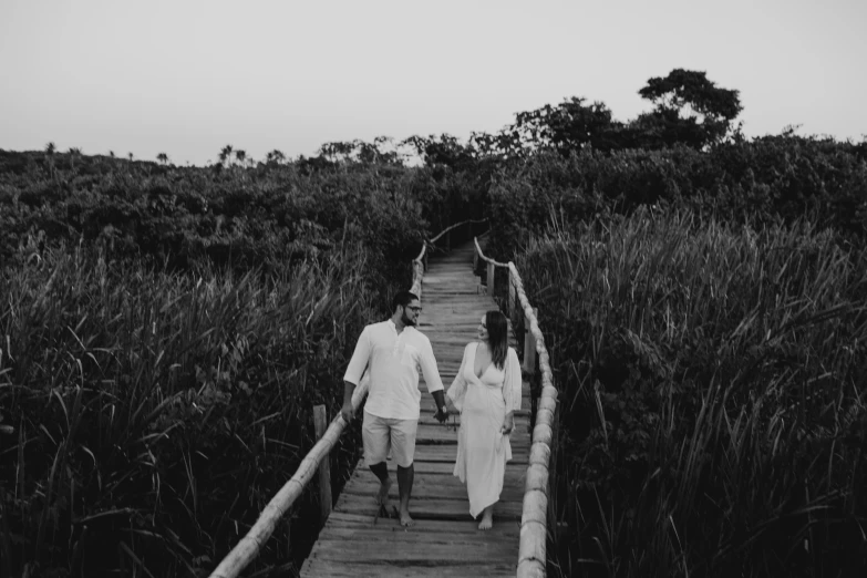 a man and woman are walking down a wooden path