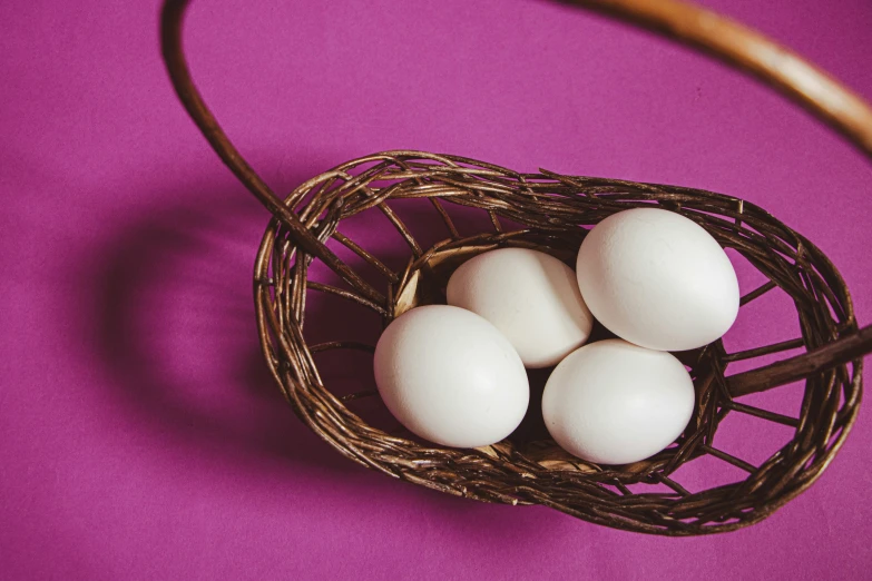 a basket of white eggs on purple background