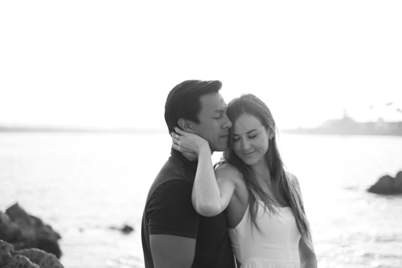 a man kissing a woman on the cheek by water