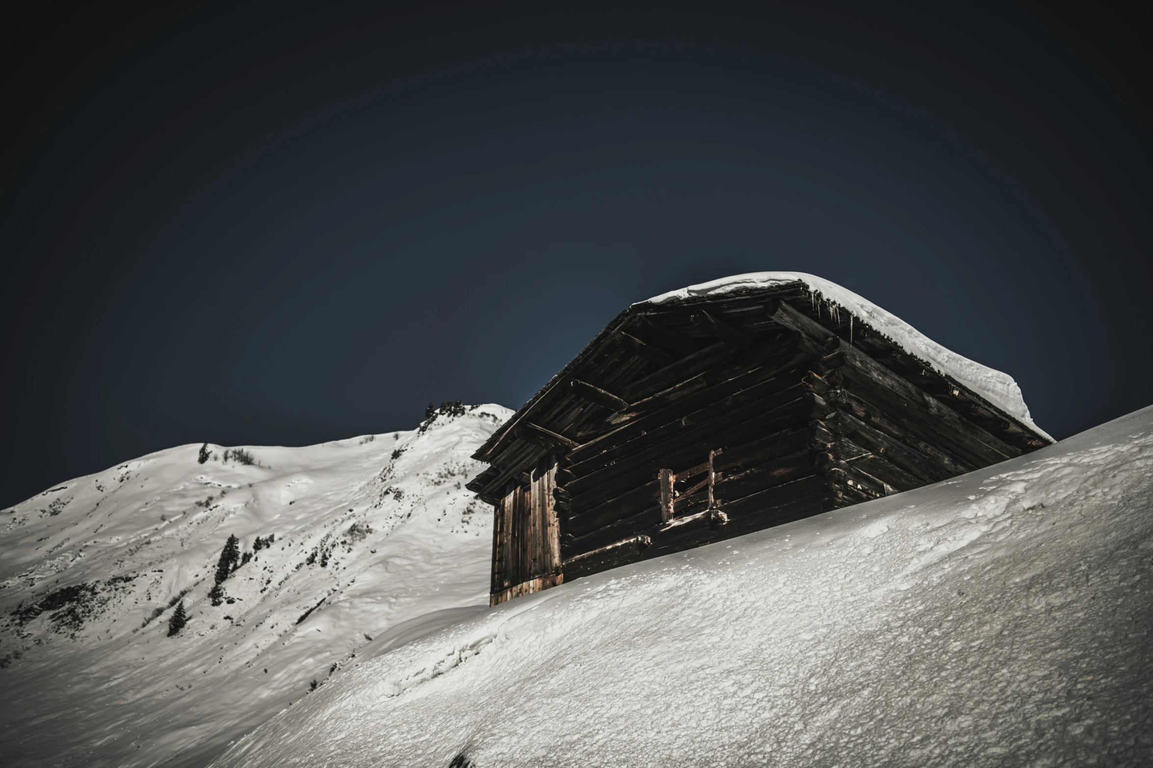 a small building on the side of a snowy mountain