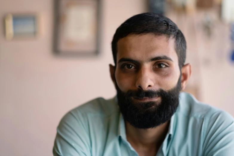 man with beard in blue shirt posing for camera