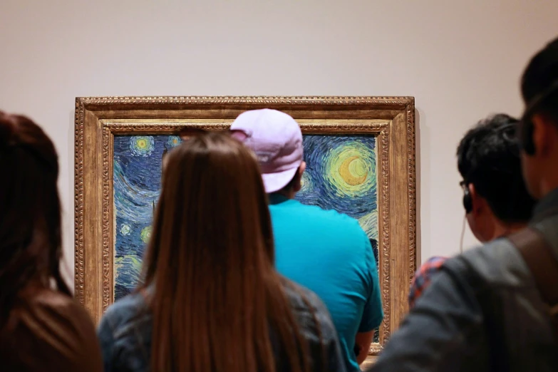 a group of people standing next to a painting