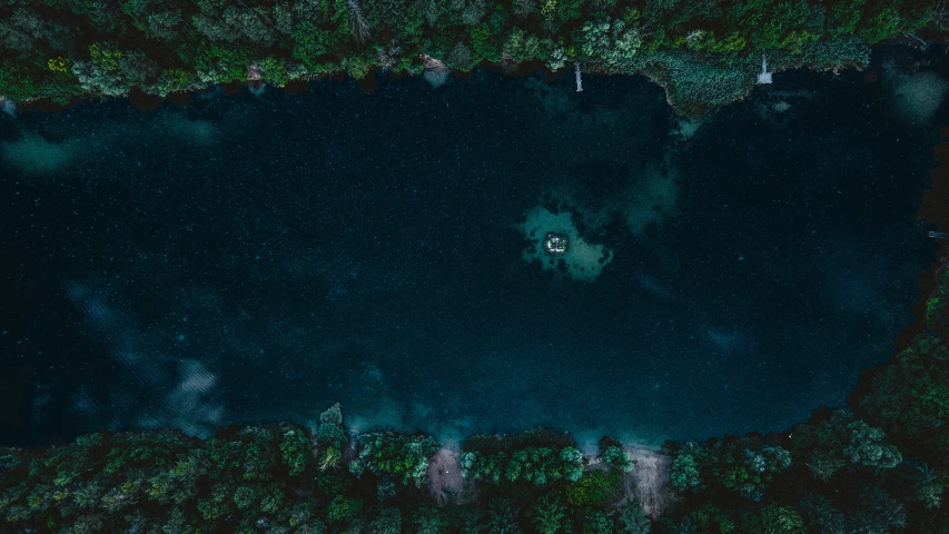 a lake is surrounded by dark green foliage