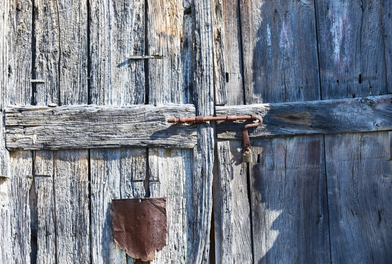 an old wooden door with a padlock and rusty handle