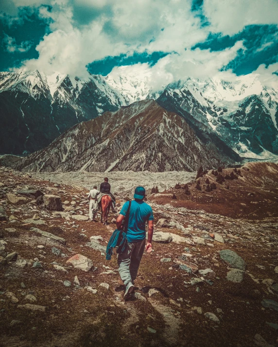 two people with backpacks walk through rocky terrain and mountains