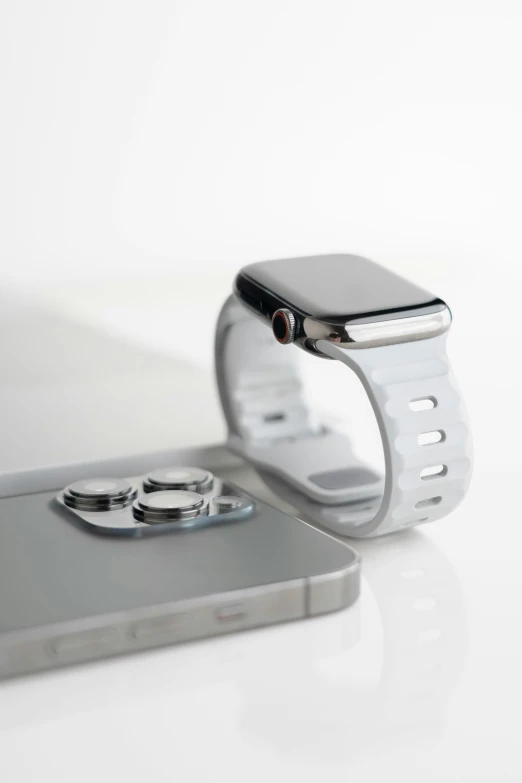 an iphone and a watch sitting on top of a white counter