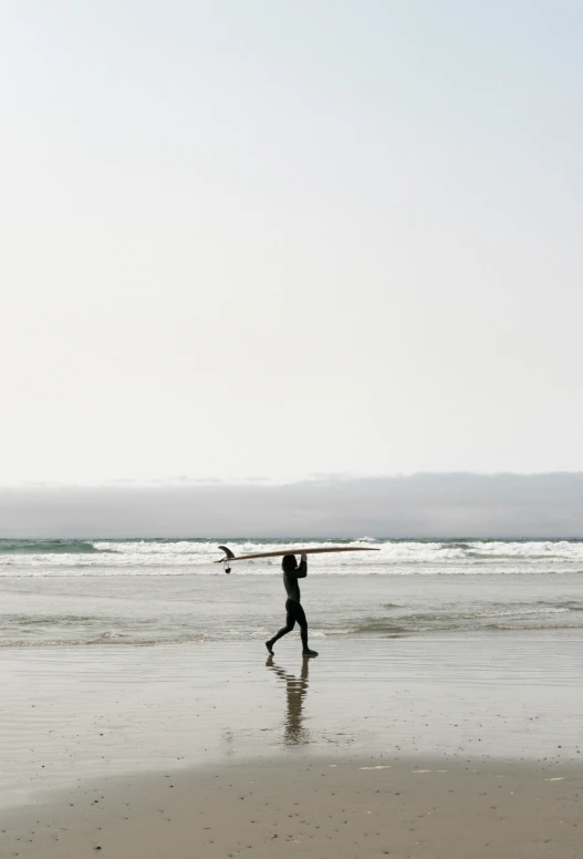 a person on the beach carrying a surf board over their head