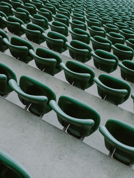 green chairs with rows of them sit in a stadium