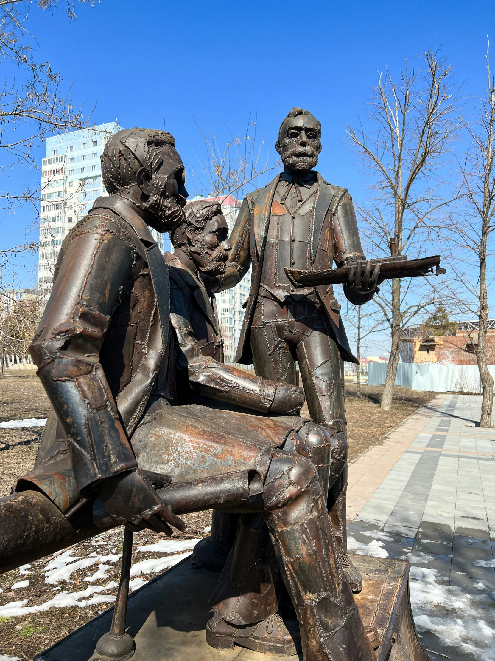 a statue of two people and a gun near a tree