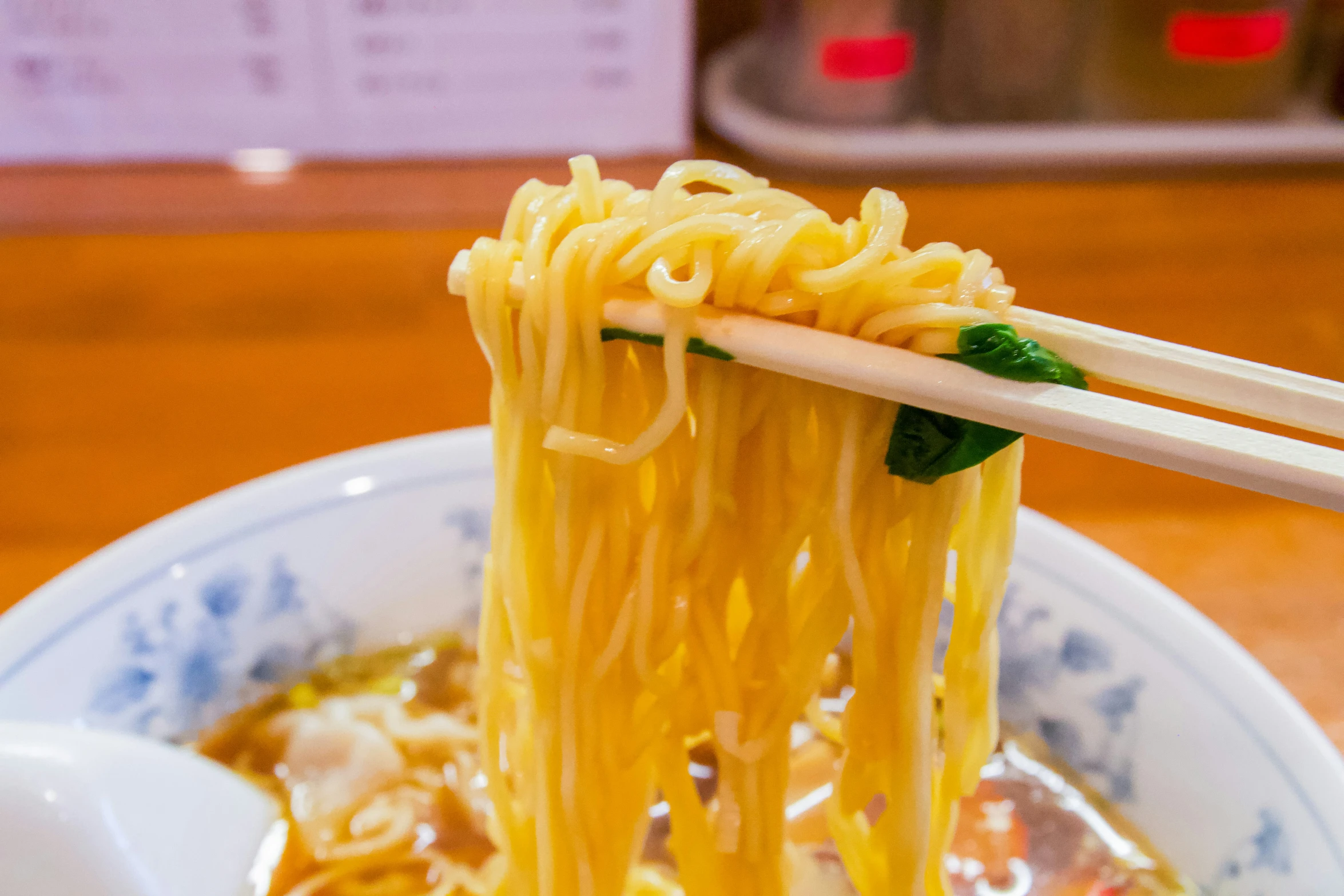 noodles being lifted from a bowl with chopsticks