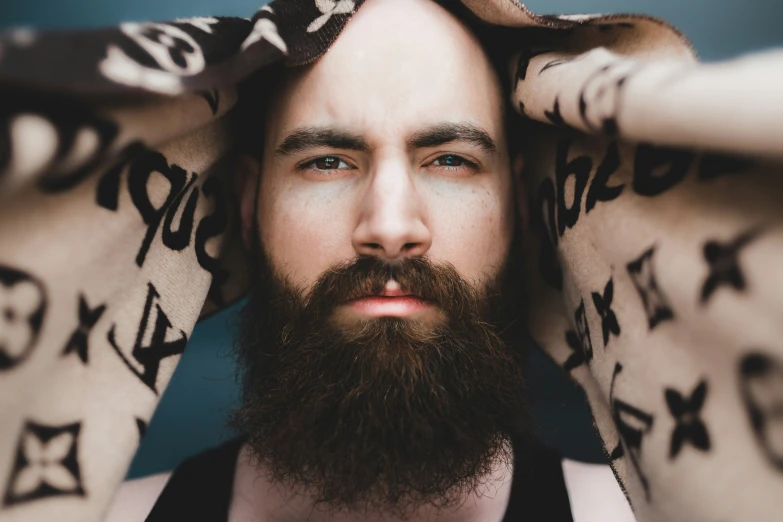 a bearded man with a large tattoo and a beard holds his hands over his head