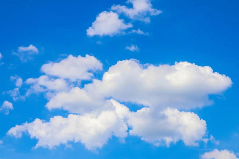 the plane is flying in the sky and the clouds are mostly white