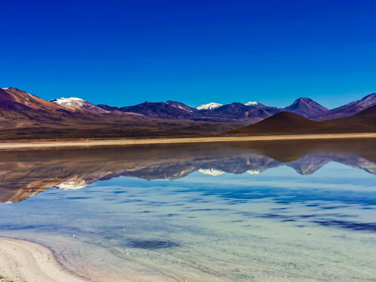 an empty beach with mountains in the background