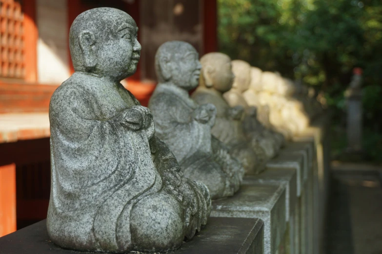 sculptures of buddhas line up against a brick wall