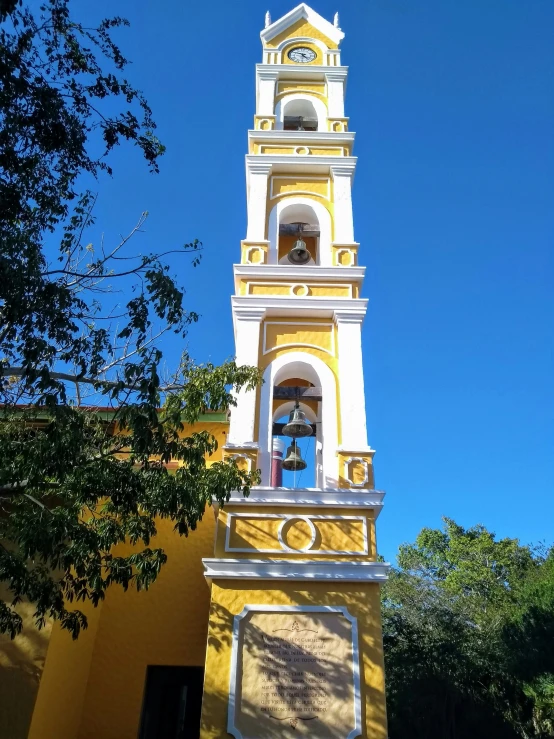 a clock tower that has bells and is yellow