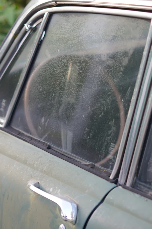 an old green car with a dirty windshield