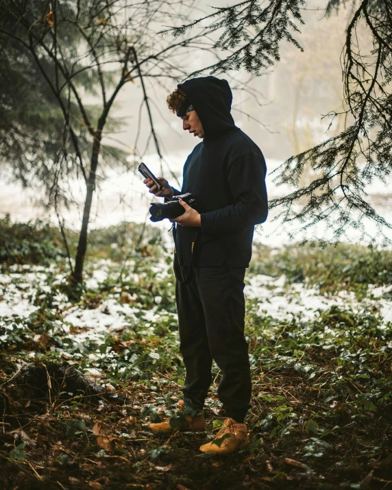 man with hoodie and mask standing in wooded area