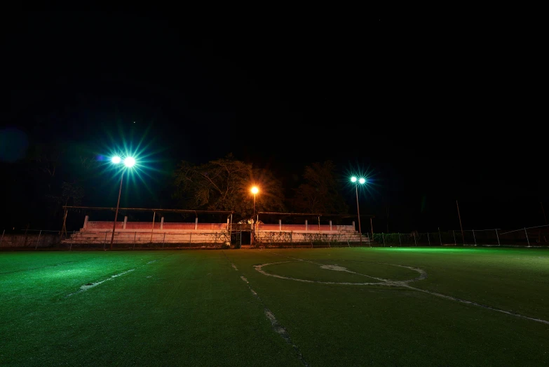 an empty soccer field at night with two lamps