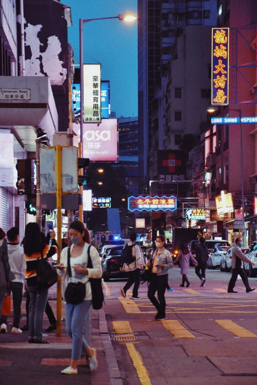 pedestrians cross an urban street at dusk