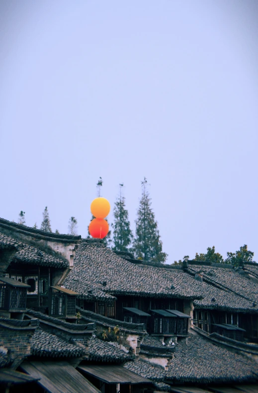 an orange balloon is hanging over a crowded roof line